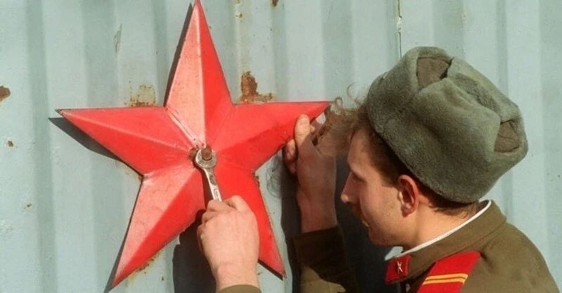 Хаалган дээрх коммунист таван хошууг тайлж авч буй Зүүн Германы цэрэг, 1990 он