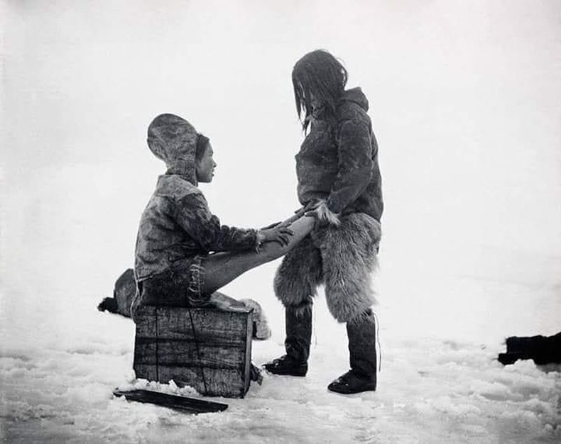 Эхнэрийнхээ хөлийг дулаацуулж өгч буй Инуит эр, 1890-ээд он