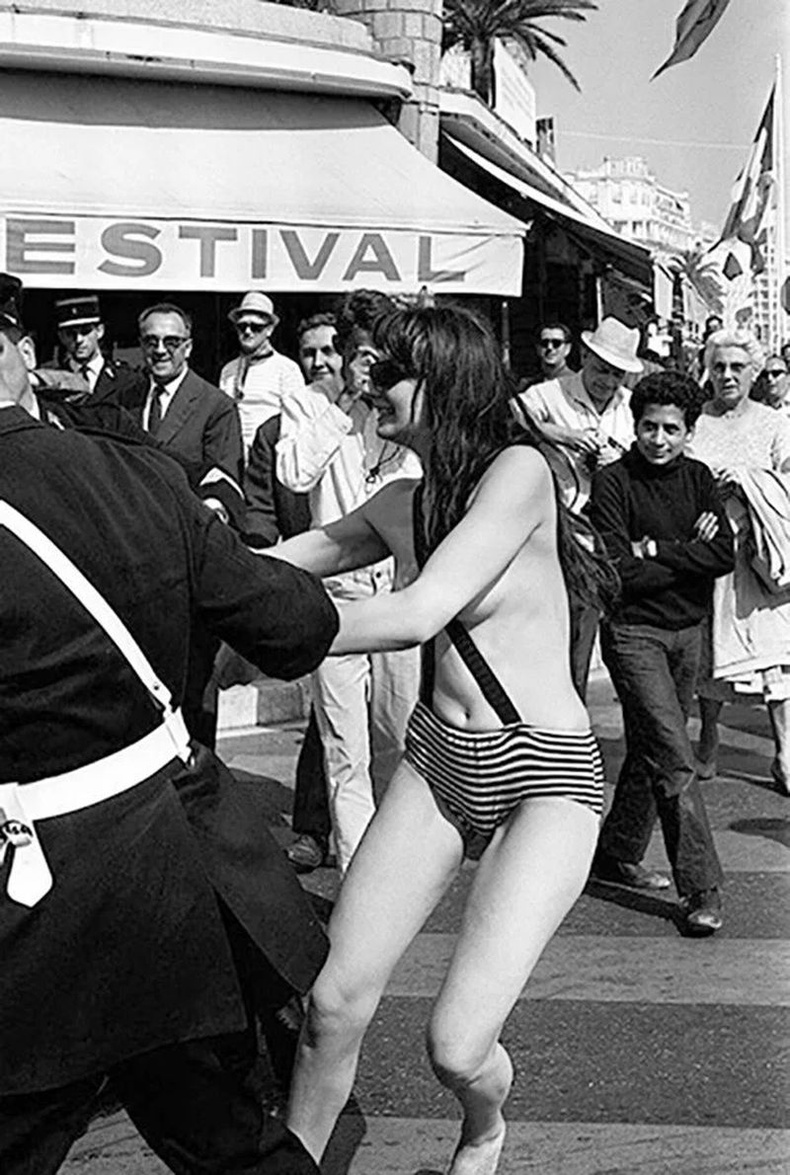 Далайн эрэг дээрх хагас нүцгэн бүсгүйг баривчилж байгаа нь - 1965 он, Канн, Франц